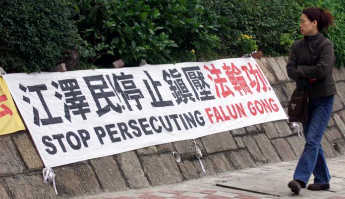 A passer-by looks at a protest banner displayed by Falun Gong followers near the Chinese de facto em..