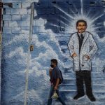 Fotografía del 27 de abril del 2021 donde se observa a un hombre que camina frente a un graffiti de José Gregorio Hernández, en Caracas. EFE/ Miguel Gutiérrez