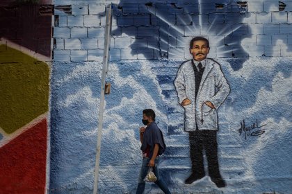 Fotografía del 27 de abril del 2021 donde se observa a un hombre que camina frente a un graffiti de José Gregorio Hernández, en Caracas. EFE/ Miguel Gutiérrez
